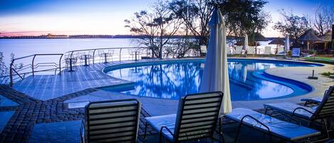 Una piscina con sillas de descanso y vistas al agua.