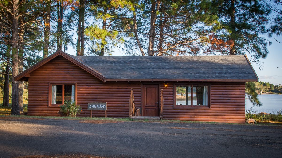 A log cabin with a sloped roof, a front door, and a window.
