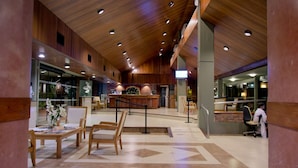 A spacious lobby with wooden paneling, a reception desk, and seating areas.