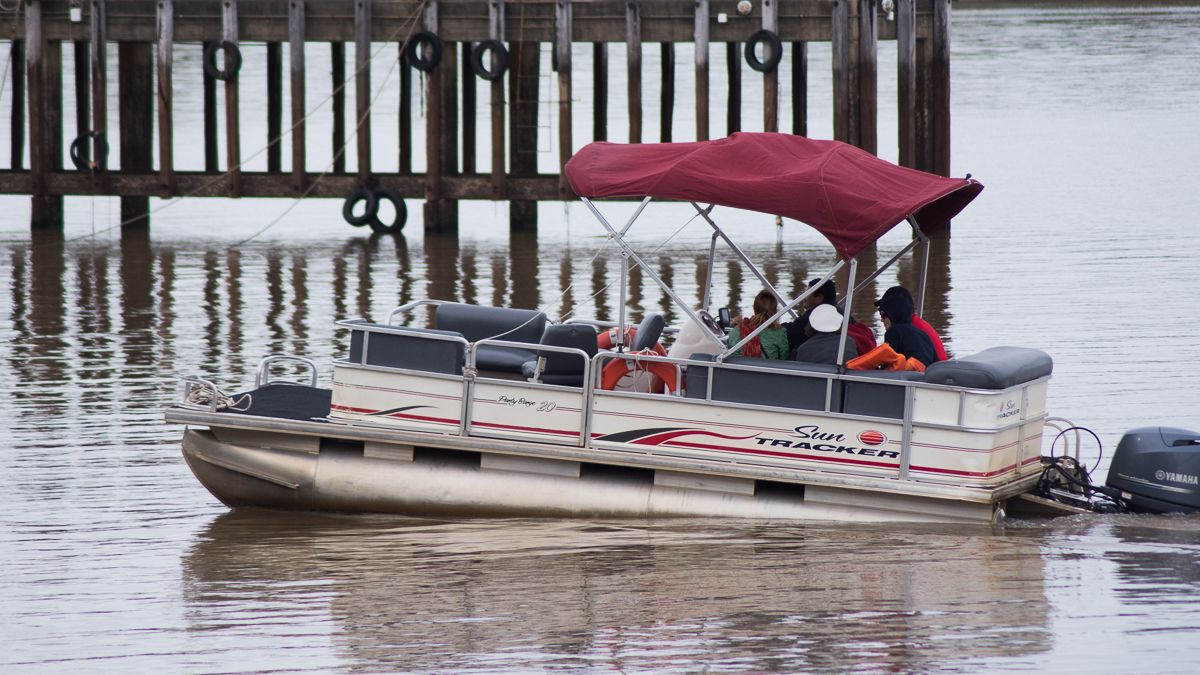 A boat with a Yamaha outboard motor, a red canopy, and passengers.