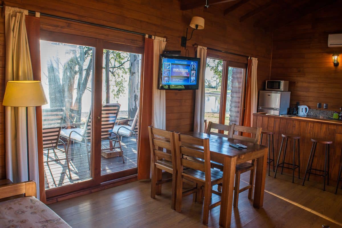 A wooden interior with a dining area, kitchen, and sliding glass doors leading to an outdoor deck.