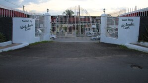 A gated entrance to Sunset Strip West Acadia Court with a metal gate and white walls. - Sunset Strip Acadia Guest Apartment (Kingston)