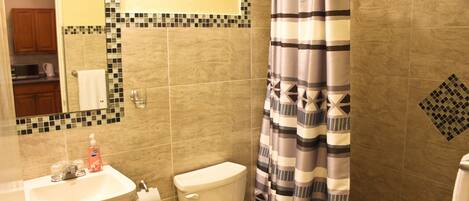 Un baño con lavamanos, inodoro y cortina de ducha.