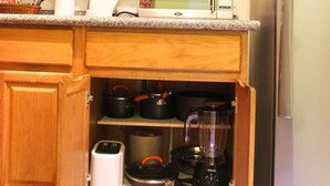 A kitchen with wooden cabinets, a microwave, a refrigerator, and various kitchen appliances. - Sunset Strip Acadia Guest Apartment (Kingston)
