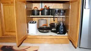 A kitchen with wooden cabinets, a blender, a toaster, and pots on the shelves. - Sunset Strip Acadia Guest Apartment (Kingston)