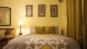 A bedroom with a bed, a nightstand, a lamp, and three framed pictures on the wall. - Sunset Strip Acadia Guest Apartment (Kingston)