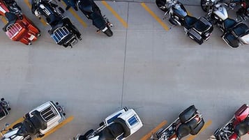 An aerial view of a parking lot with multiple motorcycles and scooters parked in designated spaces.