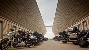 A row of motorcycles parked in a covered area with a symmetrical design and a clear sky above. - Iron Horse Inn (Whitewood)