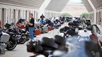 A covered motorcycle parking area with rows of motorcycles and a person standing near the entrance.