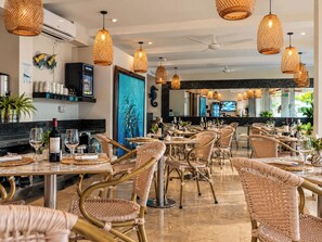 A restaurant with wicker chairs, hanging wicker lamps, and a bar area with a TV screen. - Hotel Summer Frente Al Mar (Cartagena)
