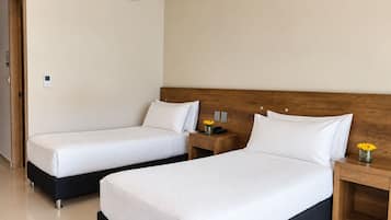 Habitación de hotel con dos camas, cabecera de madera, mesitas de noche con lámparas y aire acondicionado.