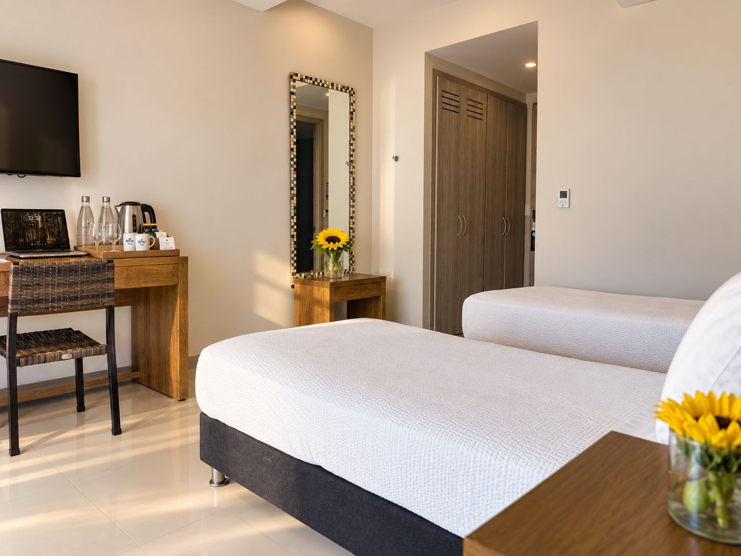Una habitación de hotel con una cama, un escritorio con una computadora portátil, una silla, un espejo y un armario.