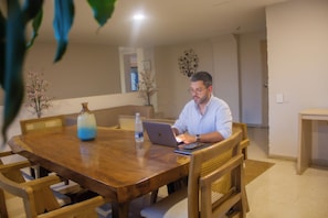 A man sitting at a wooden dining table with a laptop, surrounded by chairs and a vase. - Hotel Summer Frente Al Mar (Cartagena)