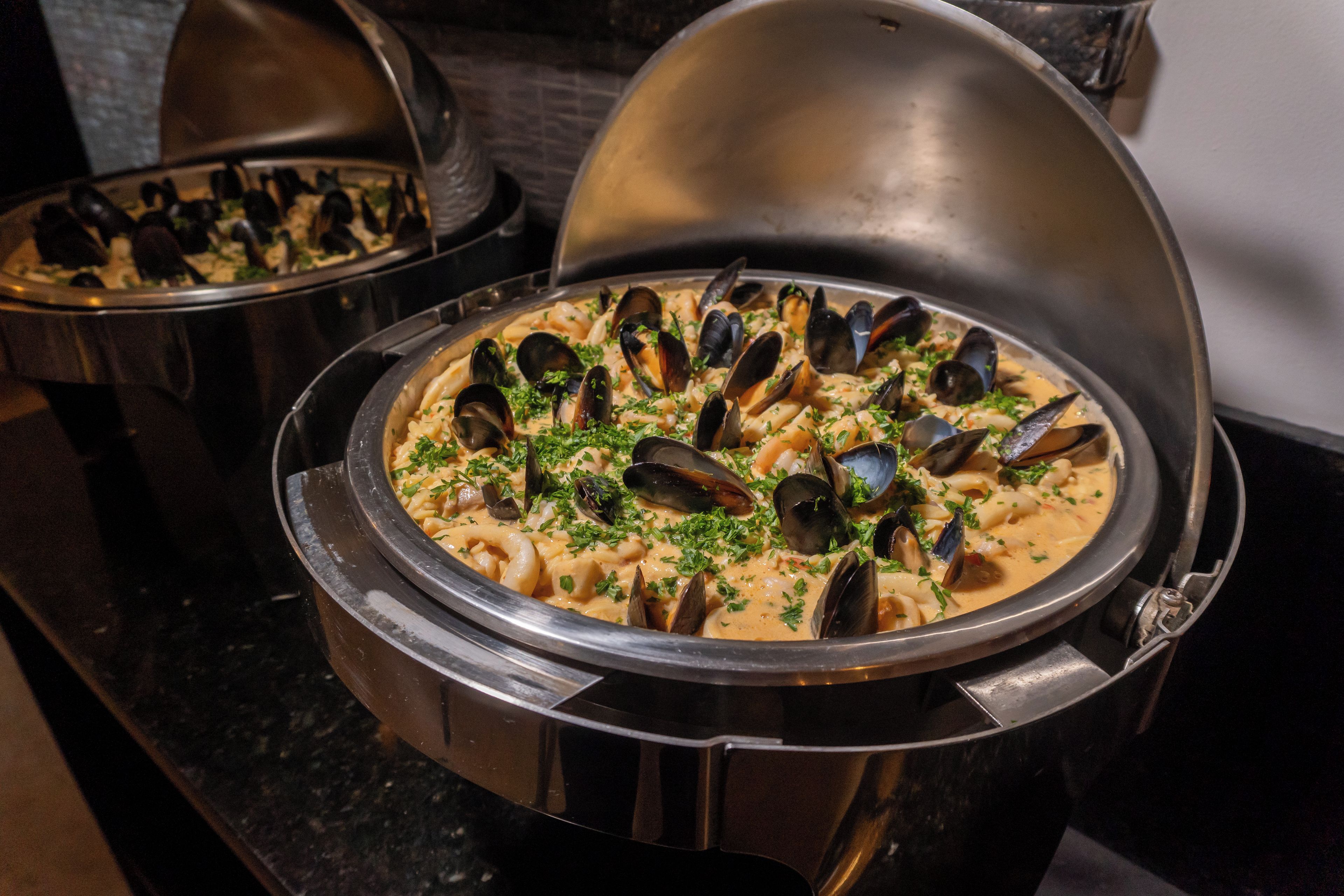 A seafood dish in a metal pot with a lid, placed on a countertop.