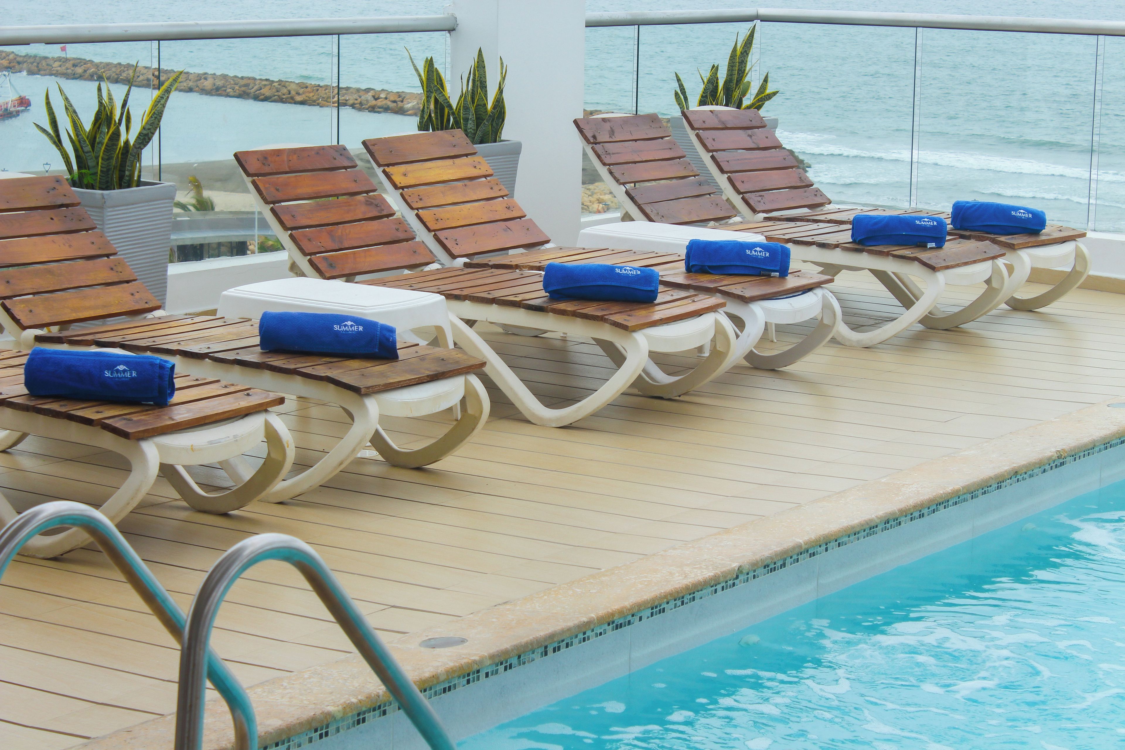 A poolside area with sun loungers and a view of the sea.