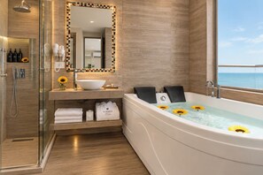 A modern bathroom with a glass-enclosed shower, a large bathtub with sunflowers, and a vanity with a mirror and toiletries. - Hotel Summer Frente Al Mar (Cartagena)