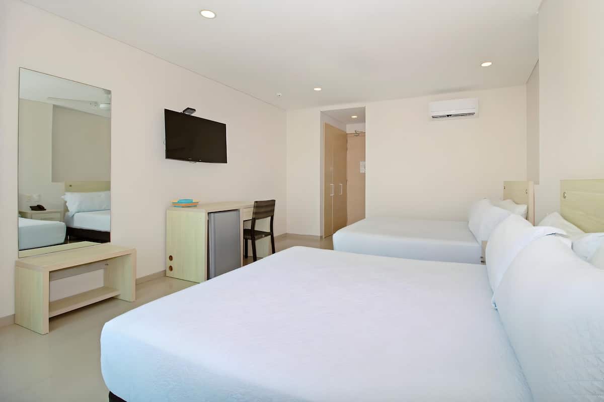 A hotel room with two single beds, a desk with a chair, a flat-screen TV, and a wardrobe.