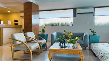 Un espacio de estar moderno con una recepción, asientos y ventanas amplias.