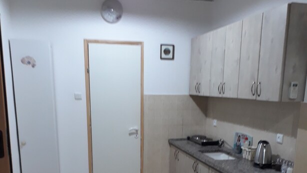 A kitchen with cabinets, a countertop, and a door. - Guest House Orlihome (Haifa)