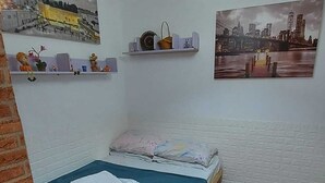 A small, well-lit room with two beds, a hanging light fixture, and two wall-mounted pictures. - Guest House Orlihome (Haifa)