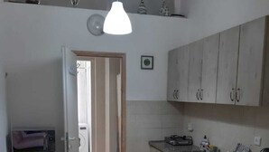 A compact kitchen with a refrigerator, a sink, and cabinets. There is a door leading to another room. - Guest House Orlihome (Haifa)