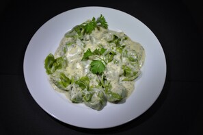 A white plate with a creamy dish garnished with parsley, served on a dark surface. - Pensión El Amigo (Lloret de Mar)