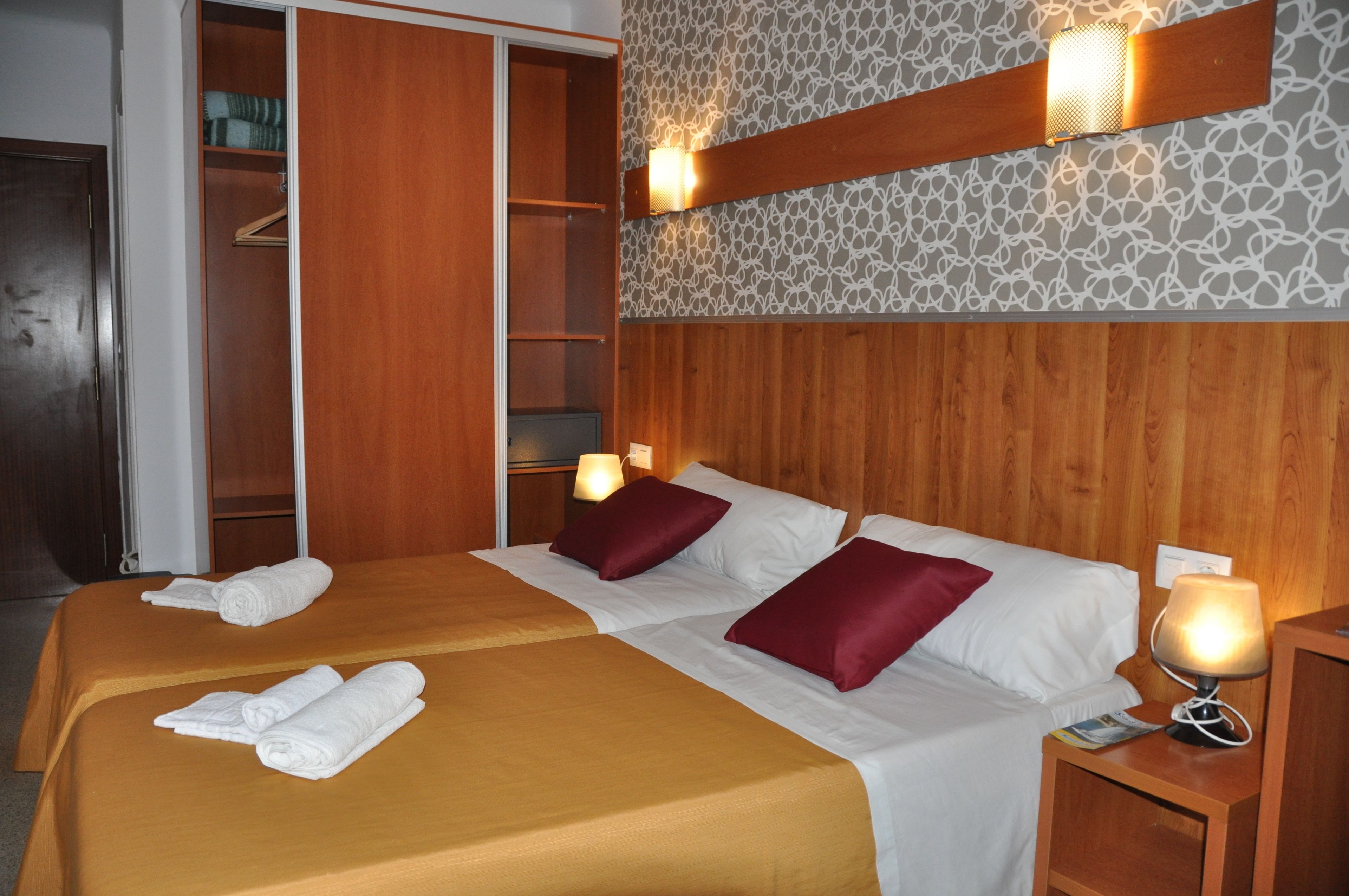 Una habitación de hotel con dos camas, un armario y una pared con diseño.