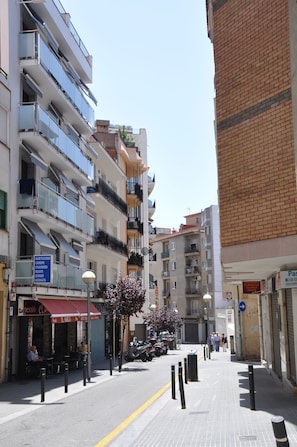 A multi-story building with balconies, a sign for 'Habitats Chambres Zimmer', and a street with parked motorcycles and pedestrians. - Pensión El Amigo (Lloret de Mar)