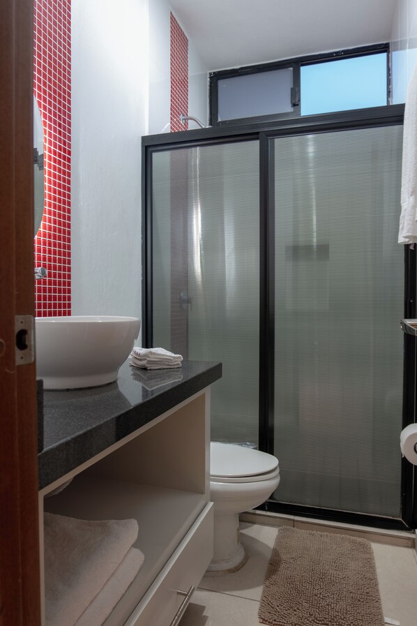 A bathroom with a white sink, a toilet, and a shower area.