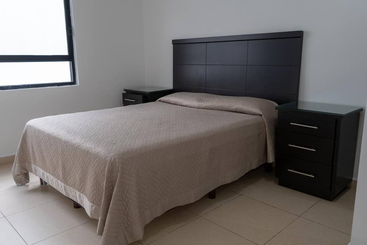 A bedroom with a bed, a nightstand, and a dresser.