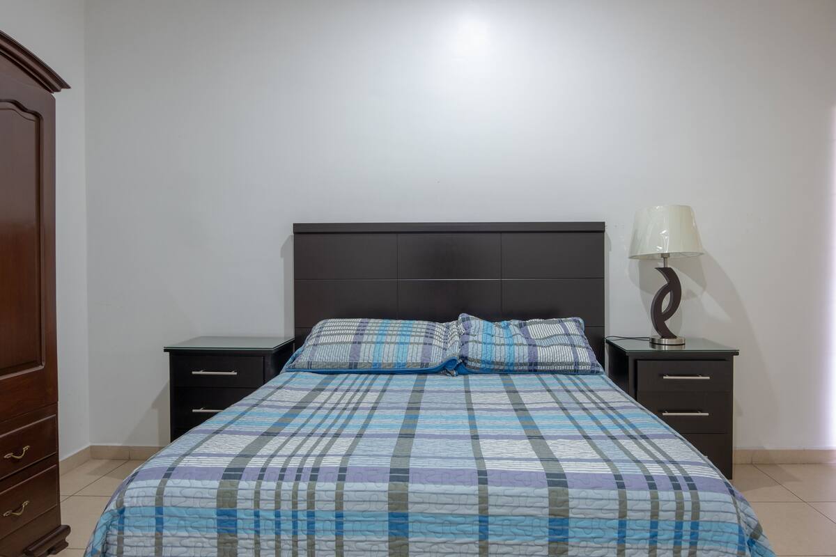 A bedroom with a bed, two bedside tables, a lamp, and a wardrobe.
