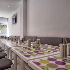 A modern conference room with a long table, grey upholstered seating, and a flat-screen TV on the wall. - Irini (Heraklion)
