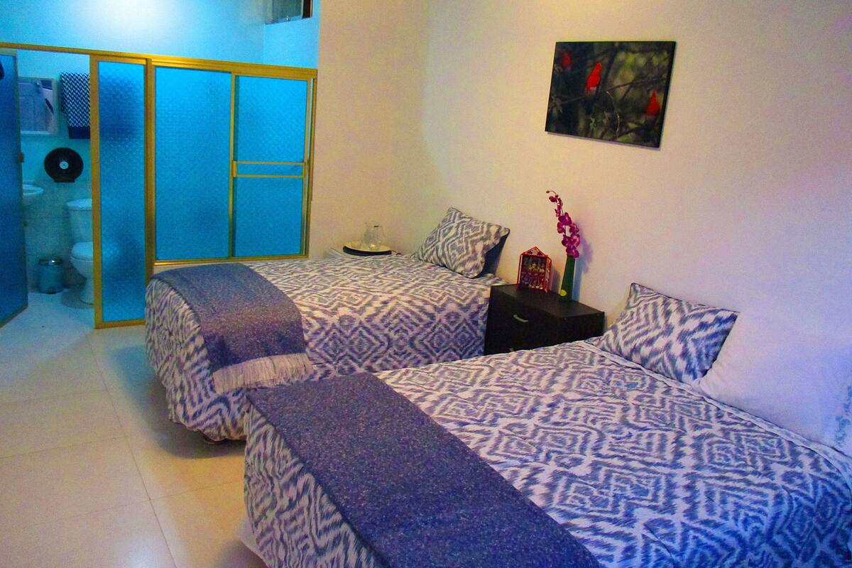 Une chambre avec deux lits, une petite table et un tableau accroché au mur.