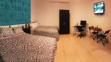 Una habitación de hotel con dos camas estampadas, un escritorio con una computadora y un televisor en la pared.