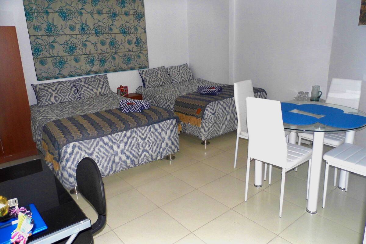 Une chambre avec deux lits, un bureau et une table à manger avec des chaises.
