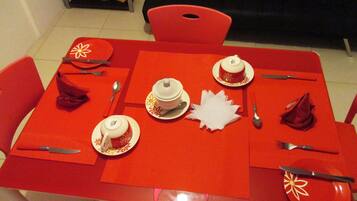 A dining table set with plates, cutlery, and a teapot.