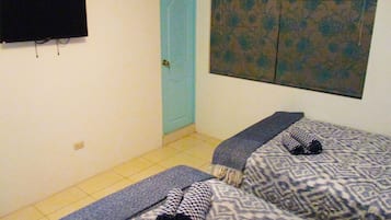 Een kamer met twee bedden, een aan de muur bevestigde televisie, een blauwe deur en een wanddecoratie met een patroon.