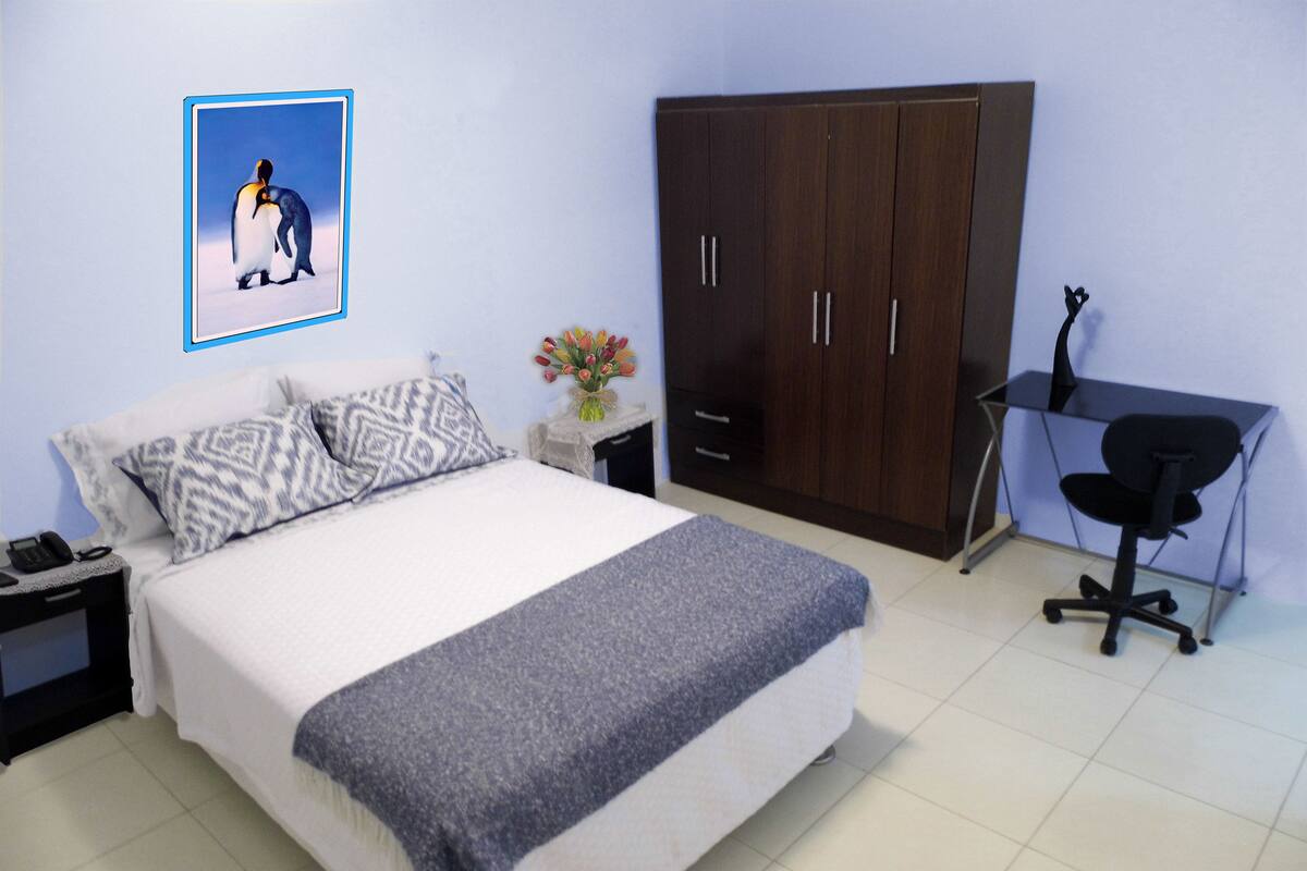 Une chambre à coucher comprenant un lit, un bureau, une armoire et une table de chevet.