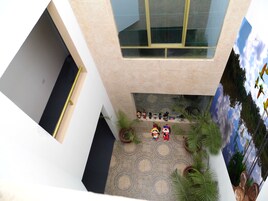 Um átrio com vários níveis, uma escadaria central, plantas em vasos e diversos objetos decorativos.