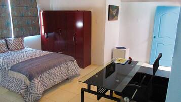 A bedroom with a bed, a desk, and a wardrobe.