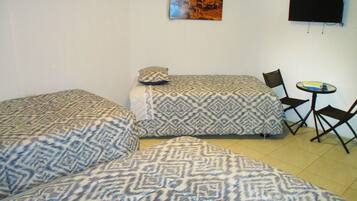 A room with two beds, a small table, and a TV on the wall.