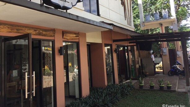 Un edificio con un letrero que dice "Calle Real Bistro" y un área de entrada cubierta con macetas.
