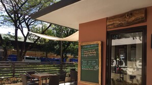 Un café al aire libre con una pizarra de menú, sillas de mimbre y una mesa.