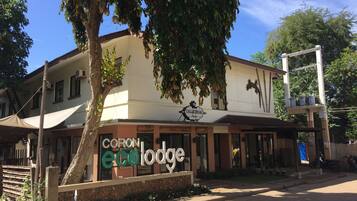 Un edifici amb un rètol que diu "CORON ECO LODGE" i un arbre al davant.