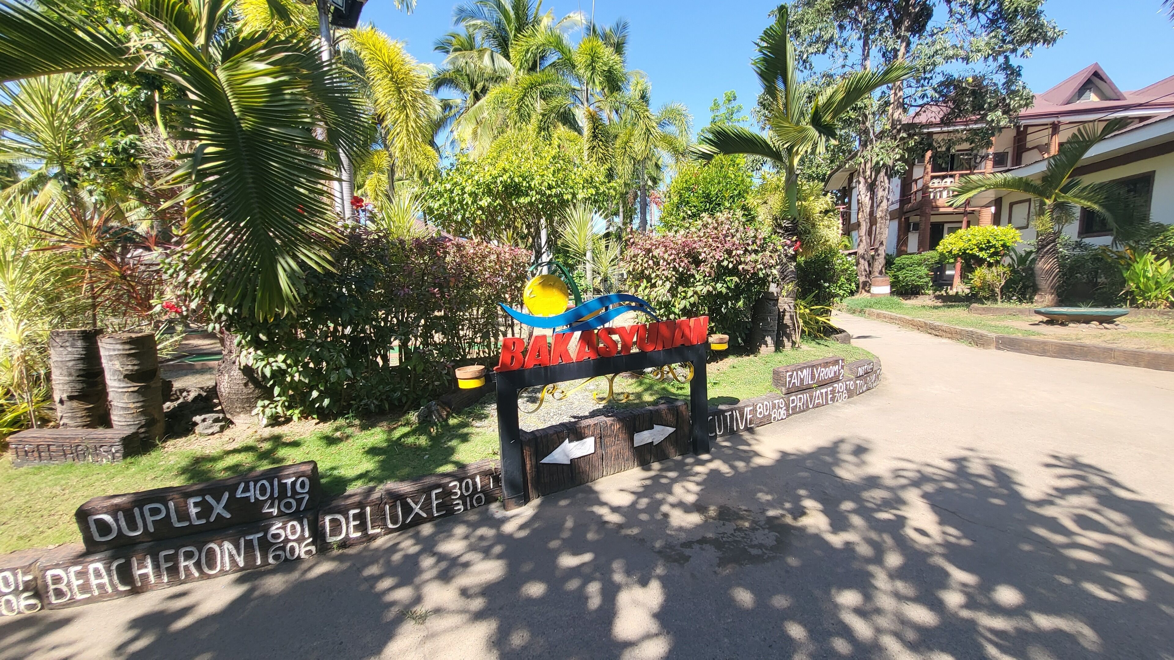 A sign for Bakasyunan with directional arrows to various accommodations like Duplex, Beachfront, and Deluxe.