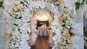 An indoor venue with a floral archway leading to a stage area with a bed and a TV screen. - Bakasyunan Resort Zambales (Iba)