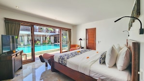 Een slaapkamer met een groot bed, een televisie en uitzicht op een zwembad.