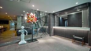Uma área de recepção moderna com divisória de vidro, balcão de atendimento, um robô e um grande arranjo floral.