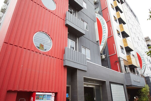 Ett hotell med en röd fasad, flera balkonger och en försäljningsautomat för Coca-Cola.