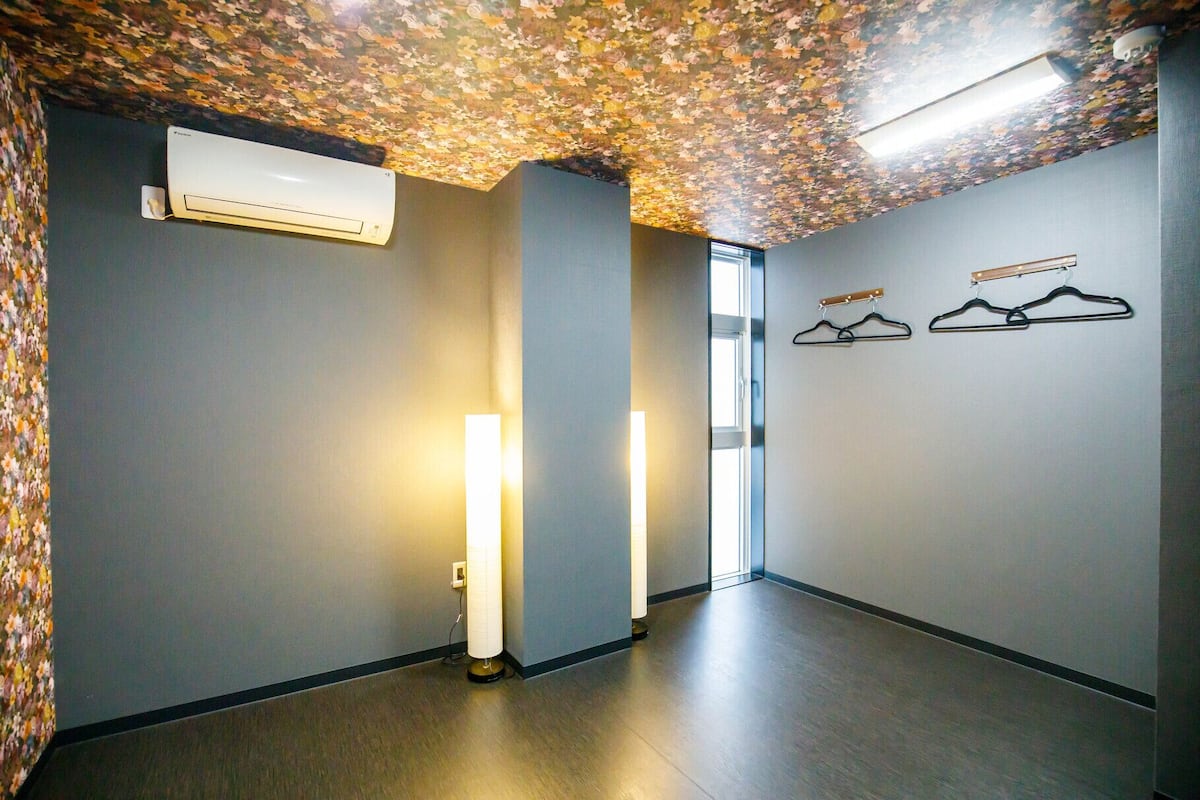 Ein Flur mit einer blumengemusterten Decke, einer Wand-Klimaanlage und zwei Wand-Knägeständern.